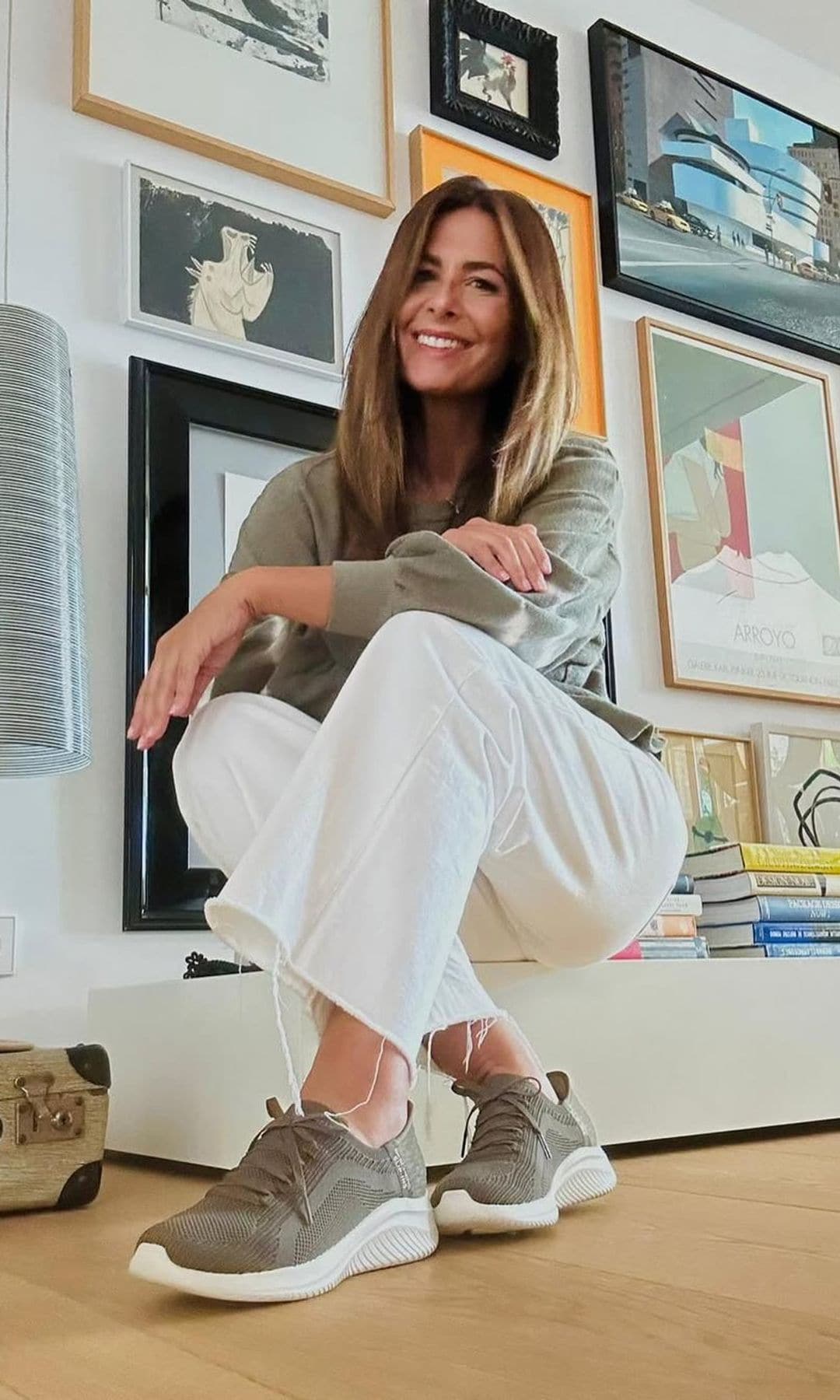 Nuria Roca en un rincón de su casa, con mueble bajo, suelo de madera y pared con cuadros