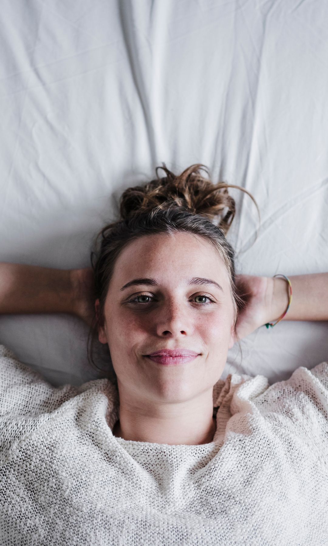 Mujer tumbada en la cama mirando a cámara