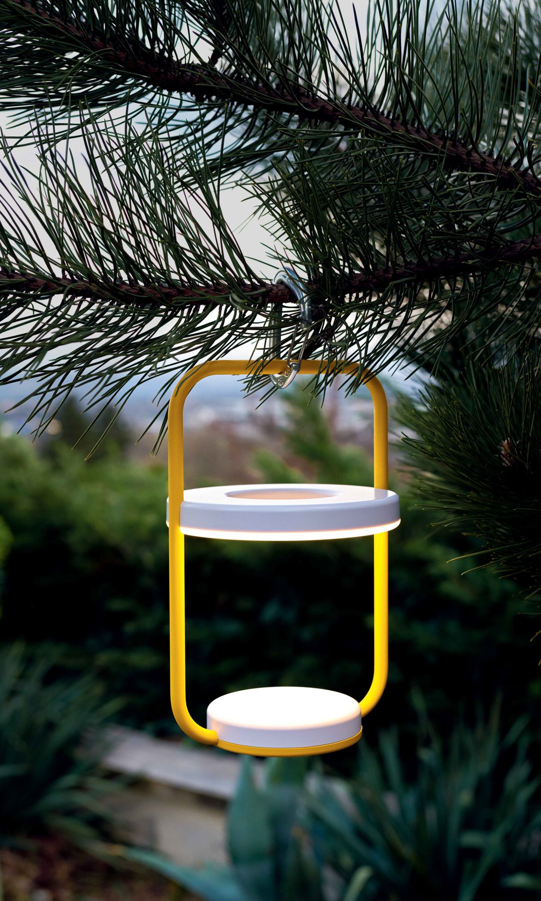 Lámpara portátil amarilla colgando de un árbol