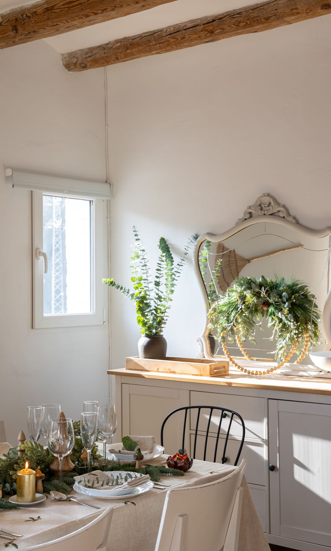 Comedor de Navidad con aparador con espejo, corona natural, bandeja, jarrón con ramas de abedul, mesa de Navidad, mantel blanco, velas, guirnalda verde en el centro