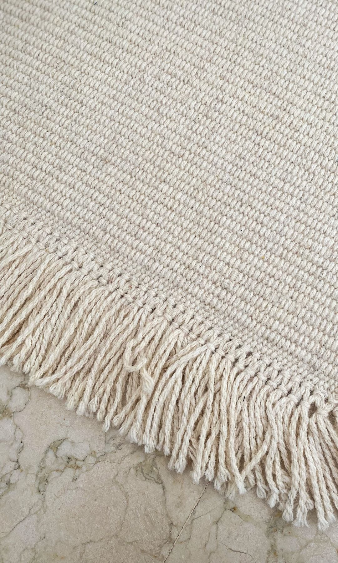 Alfombra blanca con flecos sobre suelo blanco 
