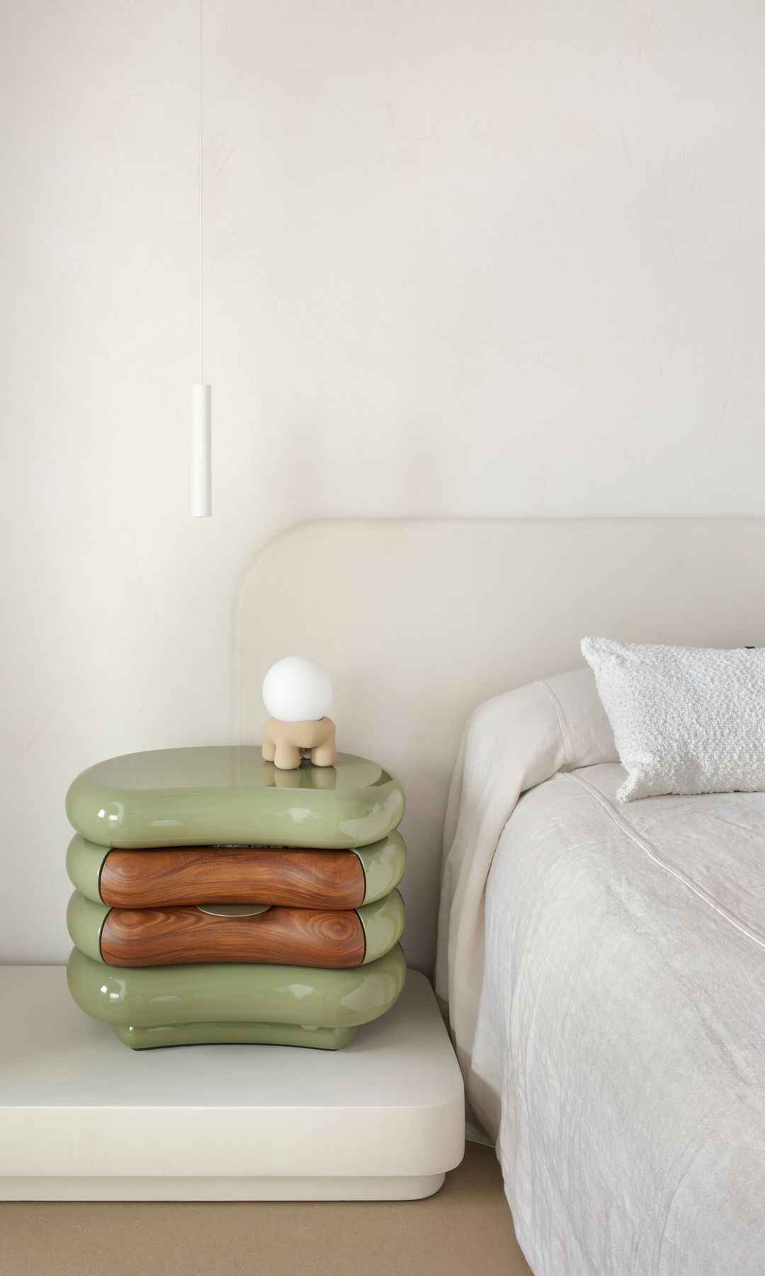 Dormitorio con cabecero tapizado en color blanco, mesita de noche de color verde, lámpara de sobremesa y lámpara de techo sobre la cama