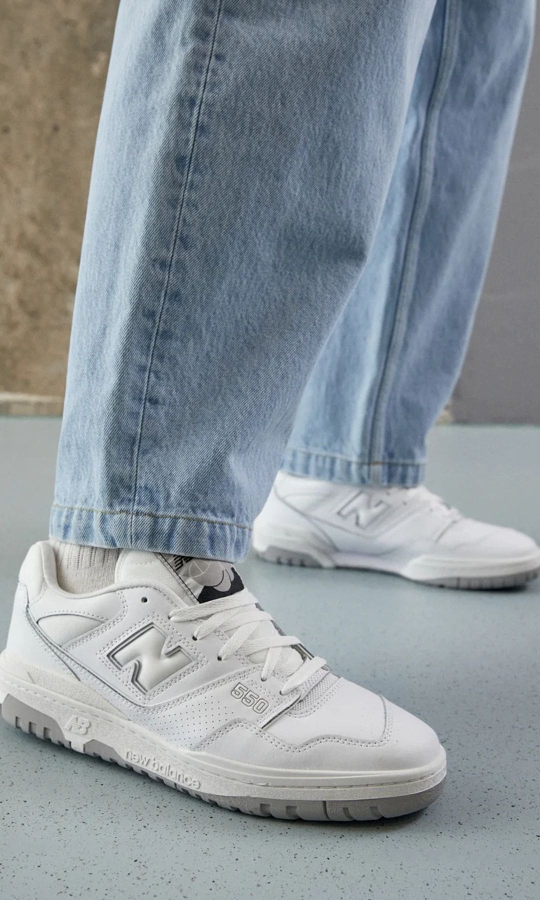 Zapatillas blancas deportivas con vaqueros en detalle de New Balance.