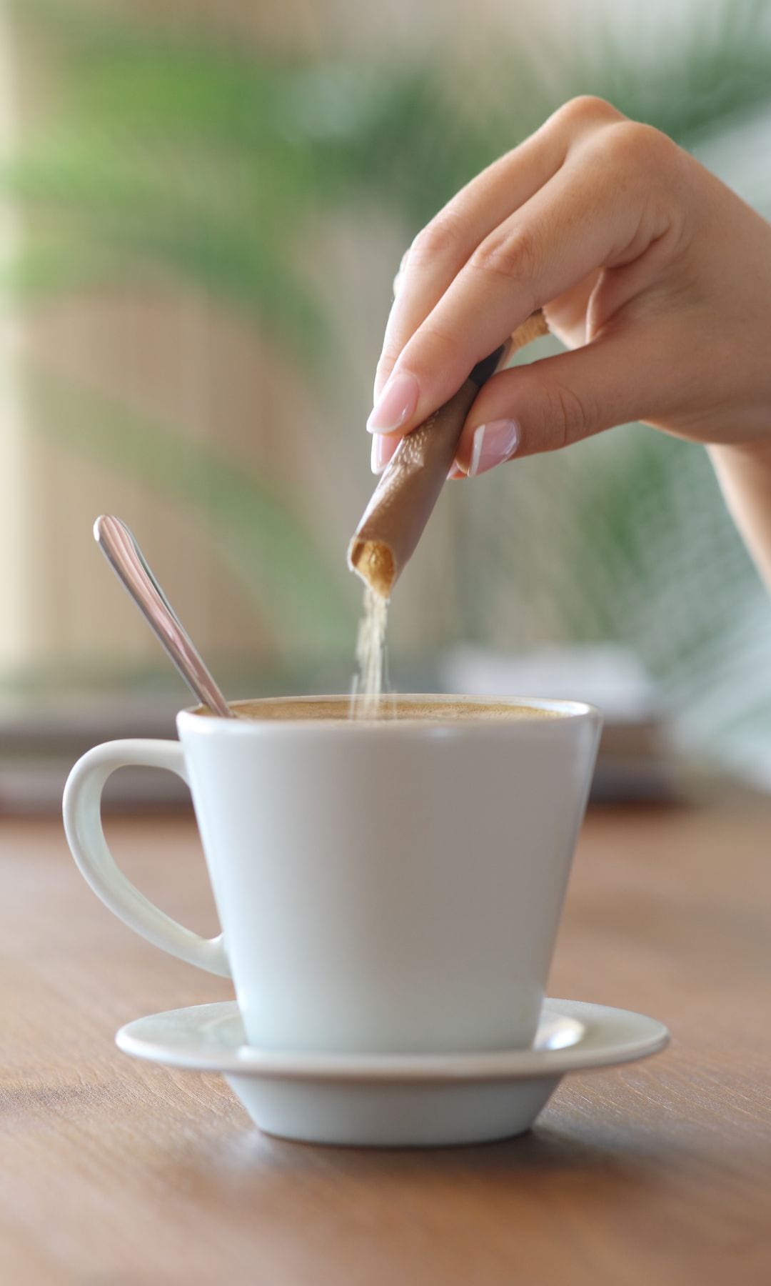 Una mujer poniendo azúcar en el café
