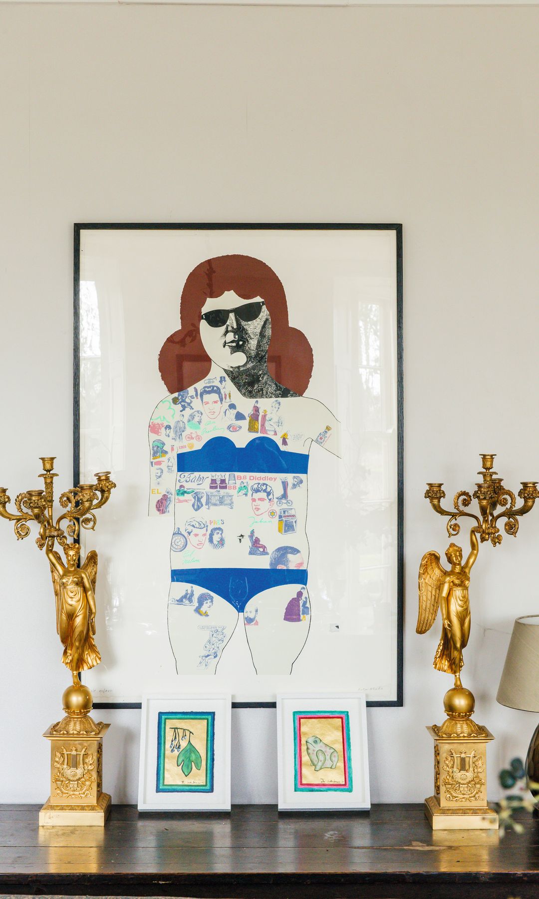 Arte mural con figura femenina y dos candelabros dorados con ángeles