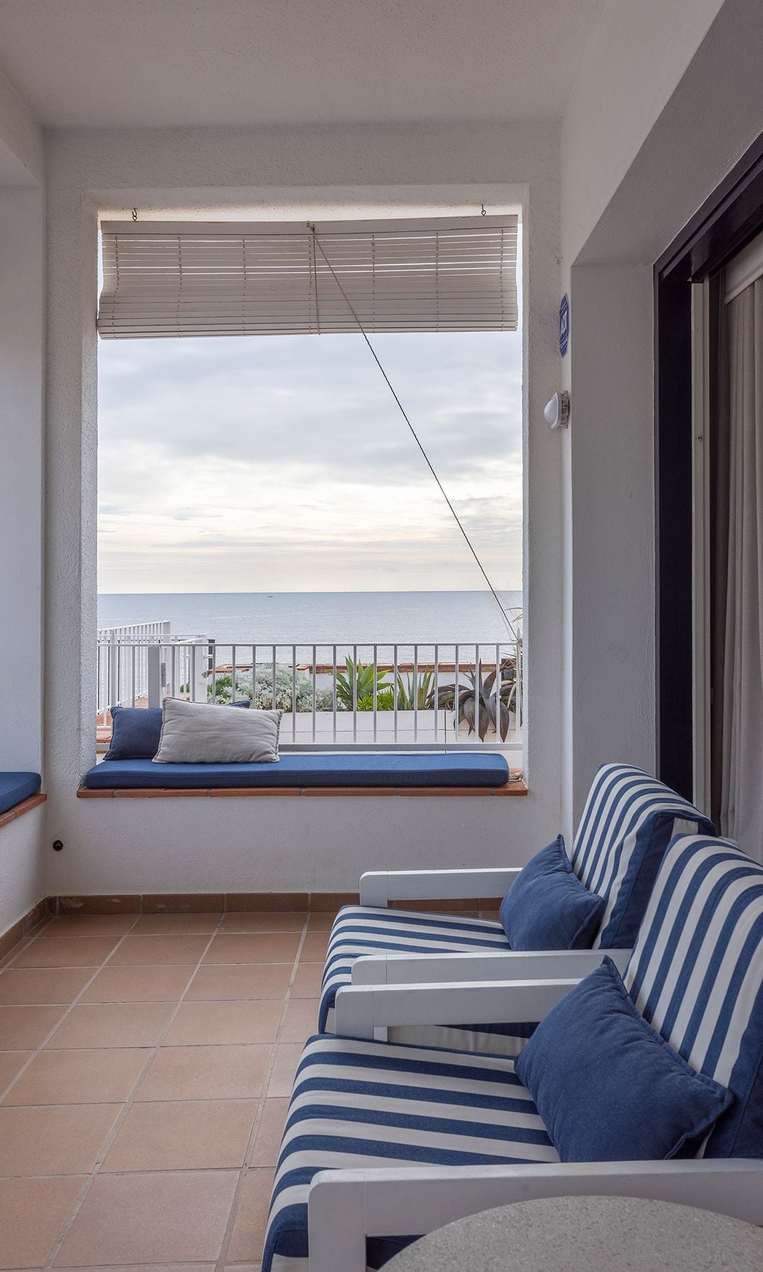 Terraza de estilo marinero, con banco de obra, butacas con asientos de rayas azul y blanco