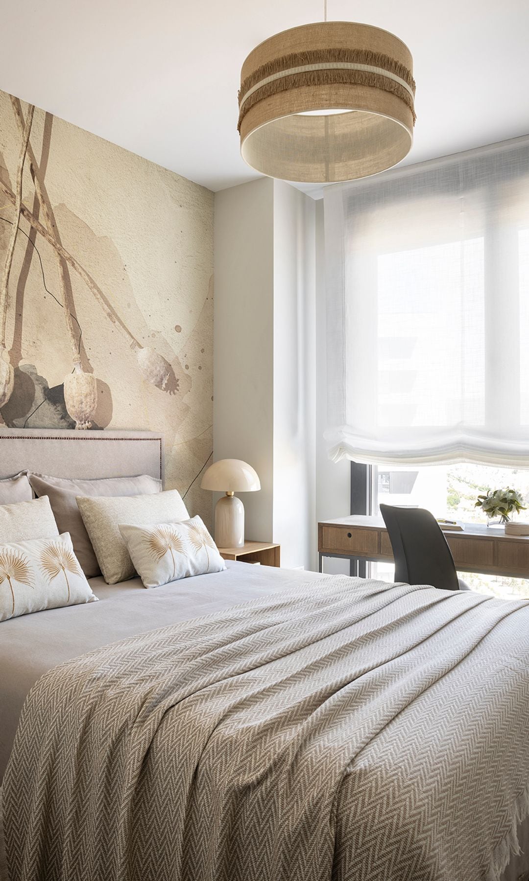 Dormitorio de matrimonio con papel pintado, escritorio bajo la ventana, ropa de cama beige, lámpara de techo, mesita de noche de madera, lámpara de sobremesa 