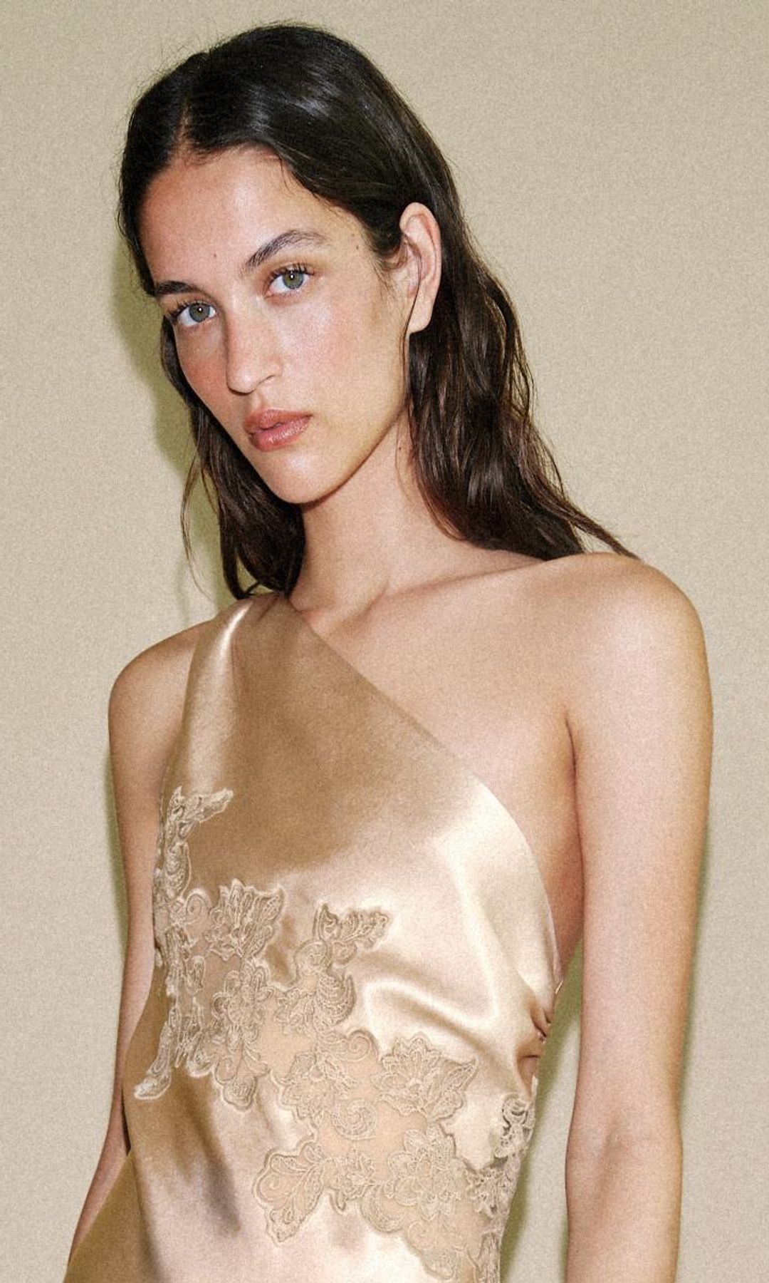 Modelo de Zara con vestido lencero asimétrico, sandalias de tacón negras y cabello suelto ondulado