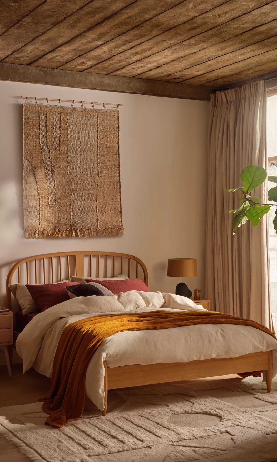 Dormitorio con tapiz en la pared, alfombra, techo de madera, cabecero de madera, cortinas, mesita de noche de madera, lámparas de sobremesa