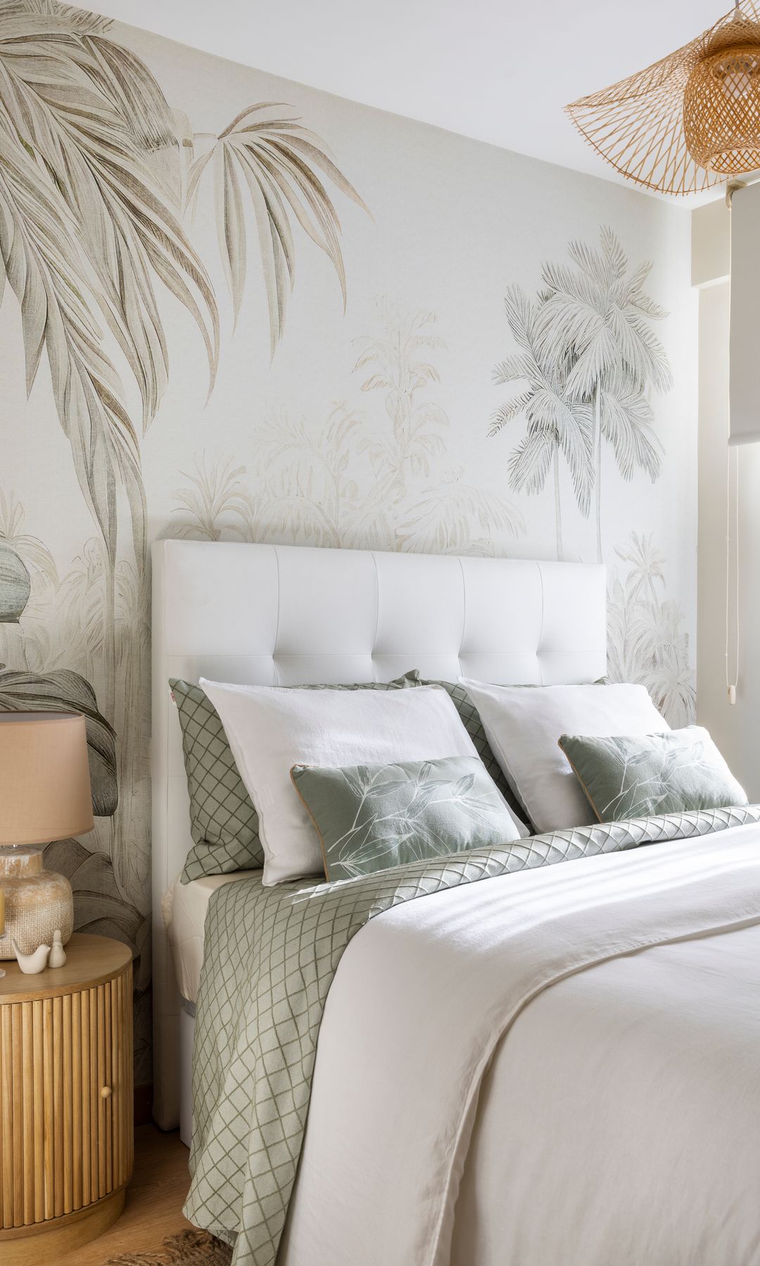 Dormitorio con papel pintado en la pared del cabecero, lámpara de fibras vegetales, cabecero tapizado, mesita de noche alistonada