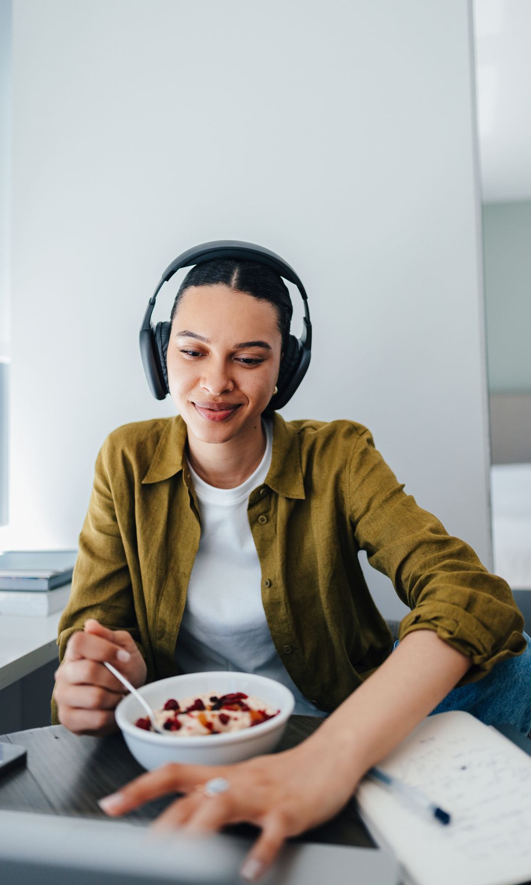 Mujer con auriculars comiendo delante del ordenador