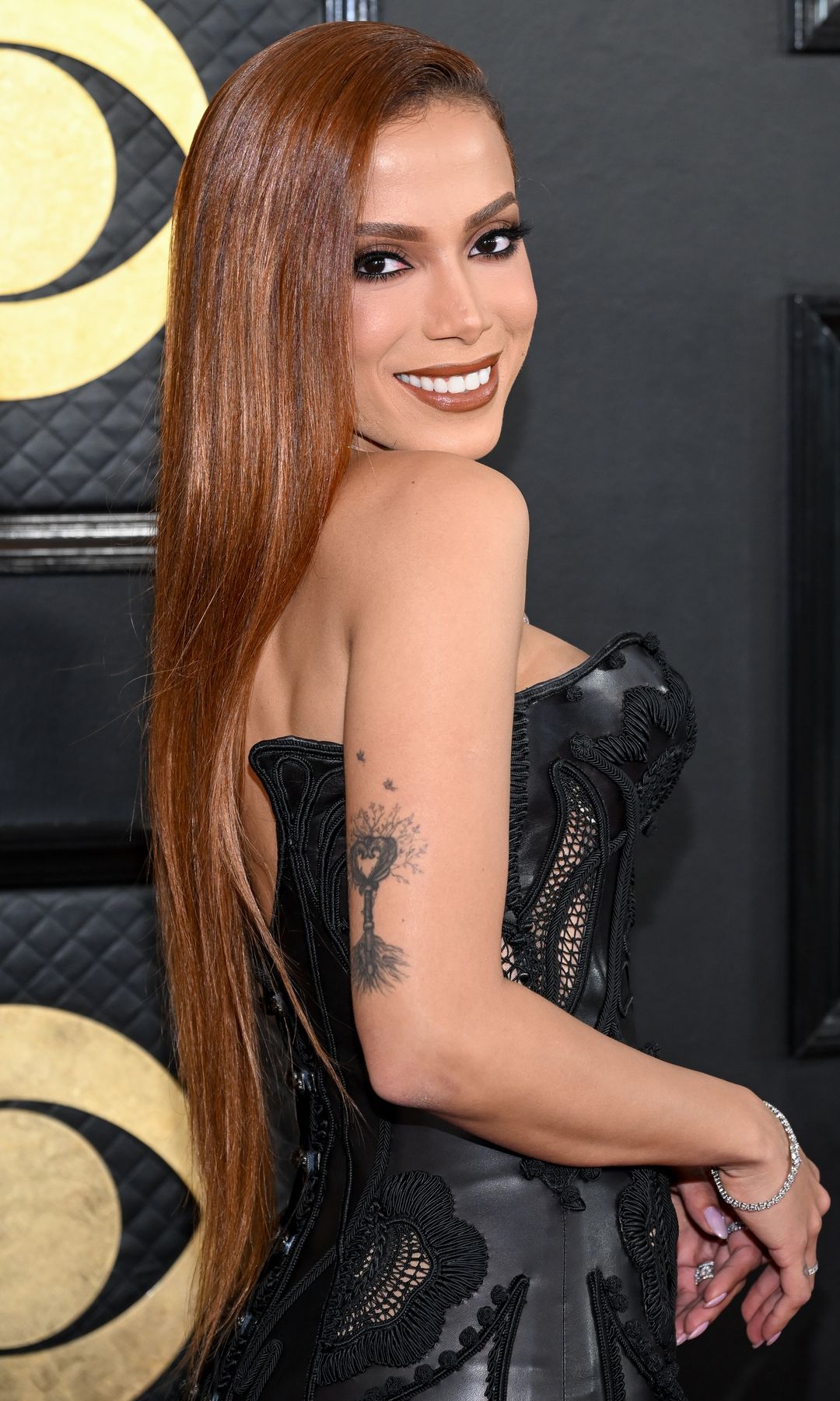 Anitta con melena XL cobriza y vestido de cuero negro