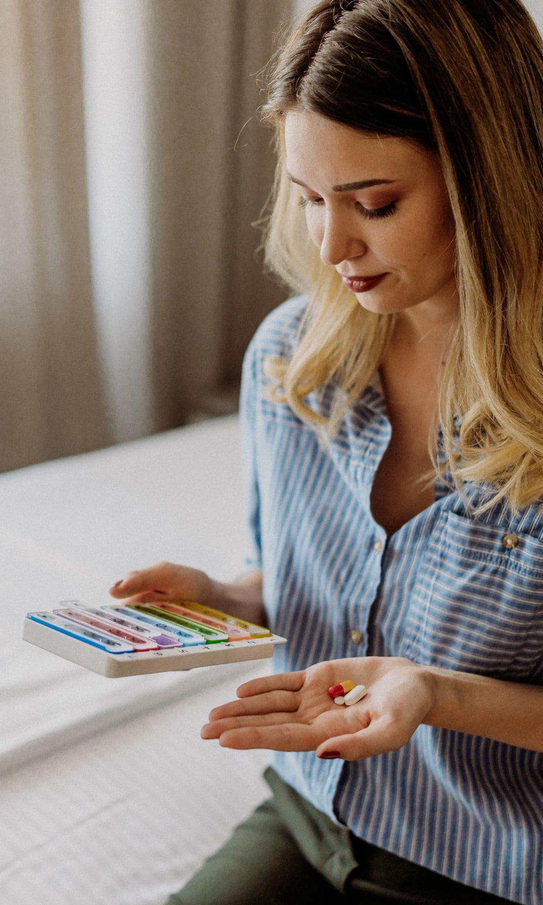 mujer mirando sus suplementos alimenticios en un pastillero