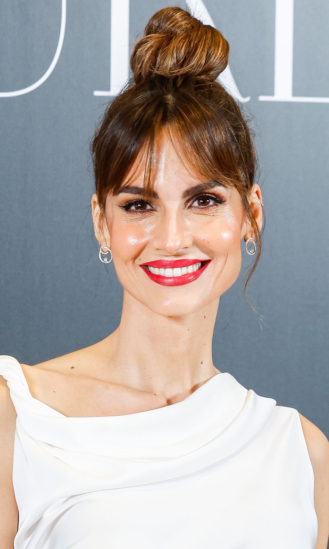 Ariadne Artiles en una fiesta con moño alto, vestido blanco y labial rojo