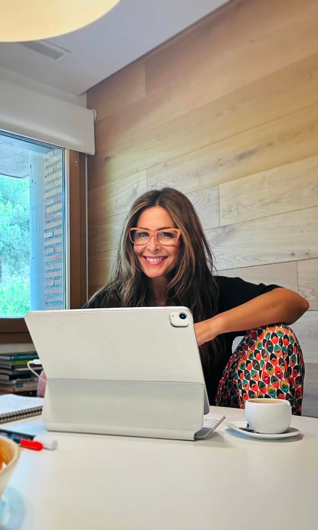 Nuria Roca en la cocina de su casa con el ordenador y un café