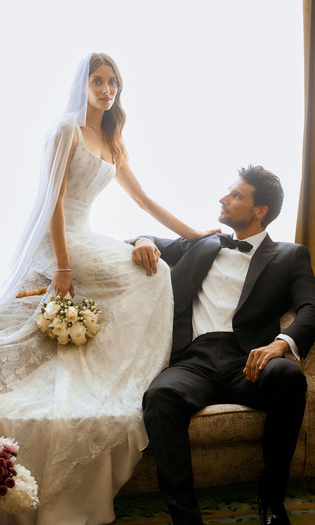 La modelo, con vestido corset con bordados en plata y velo de tul fantasía, de Rosa Clará; pulsera pavé de diamantes y oro blanco, de Rabat, y ramo clásico de rosas blancas, de Casa Florida. El modelo viste total look, de Hackett