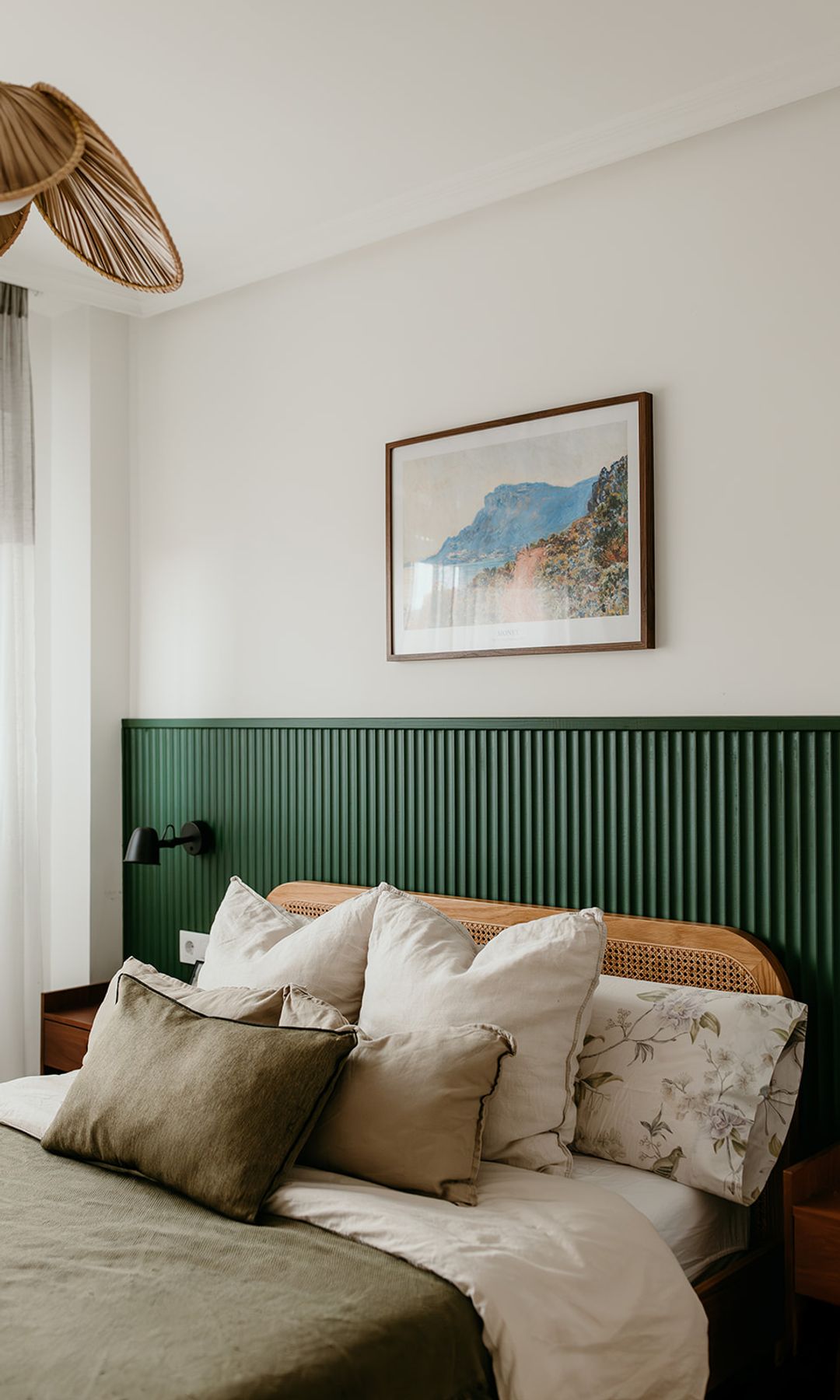 Dormitorio con pared de cabecero de lamas de madera verde oscuro de pared a pared, cojines, cabecero de rejilla, lámpara de techo de fibras vegetales