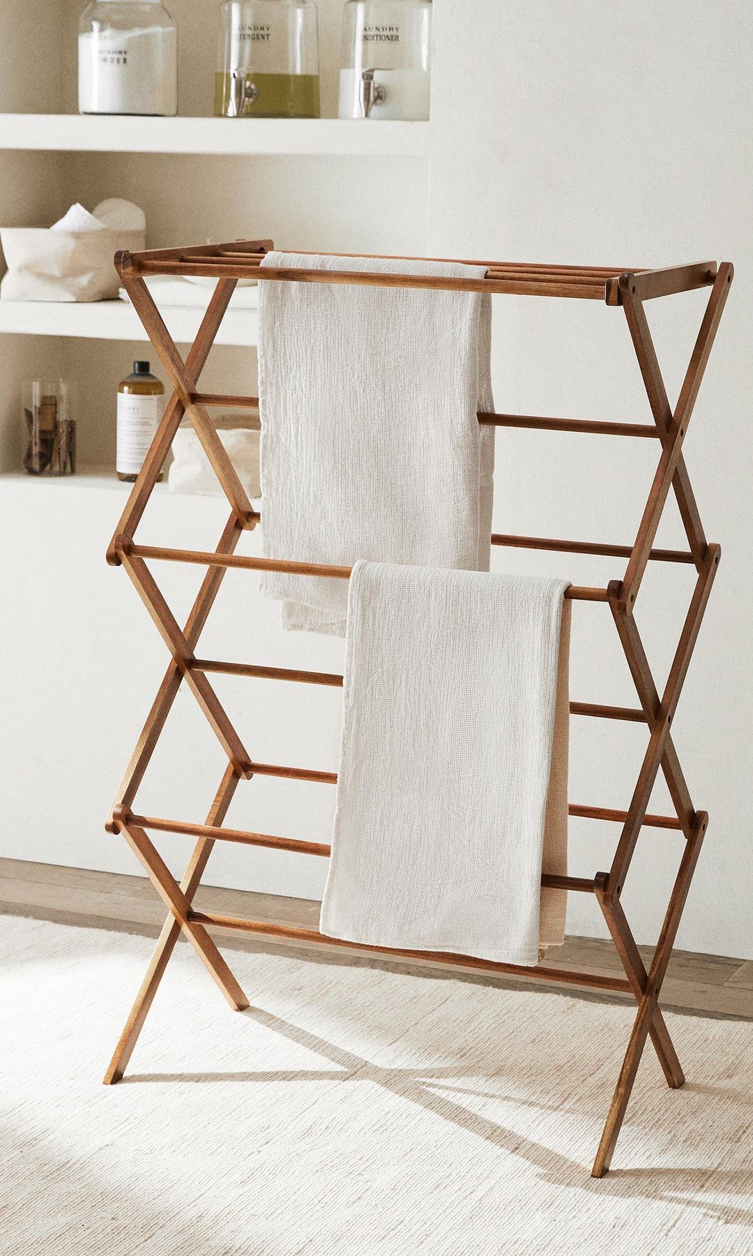 Tendedero plegable de madera con toallas y estantería de obra con botes 