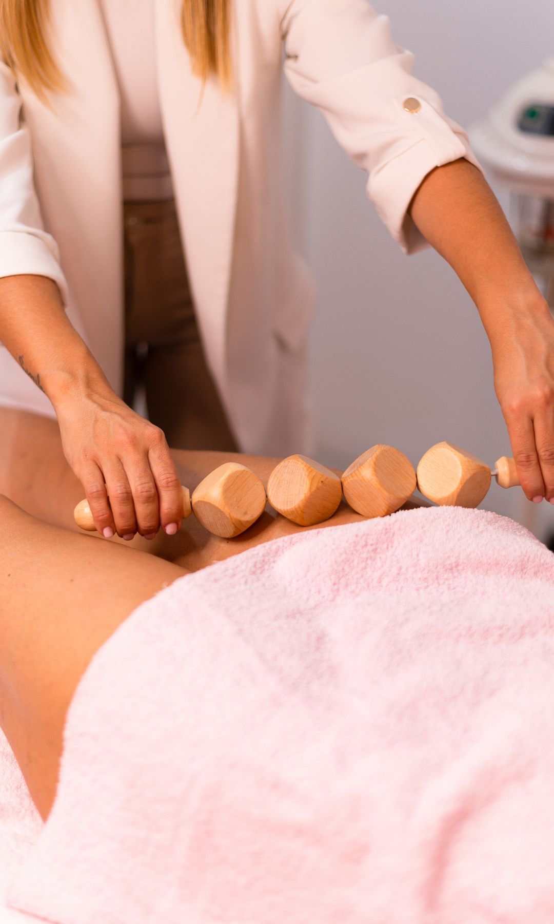 Mujer recibiendo un masaje de terapia con madera en un spa.
