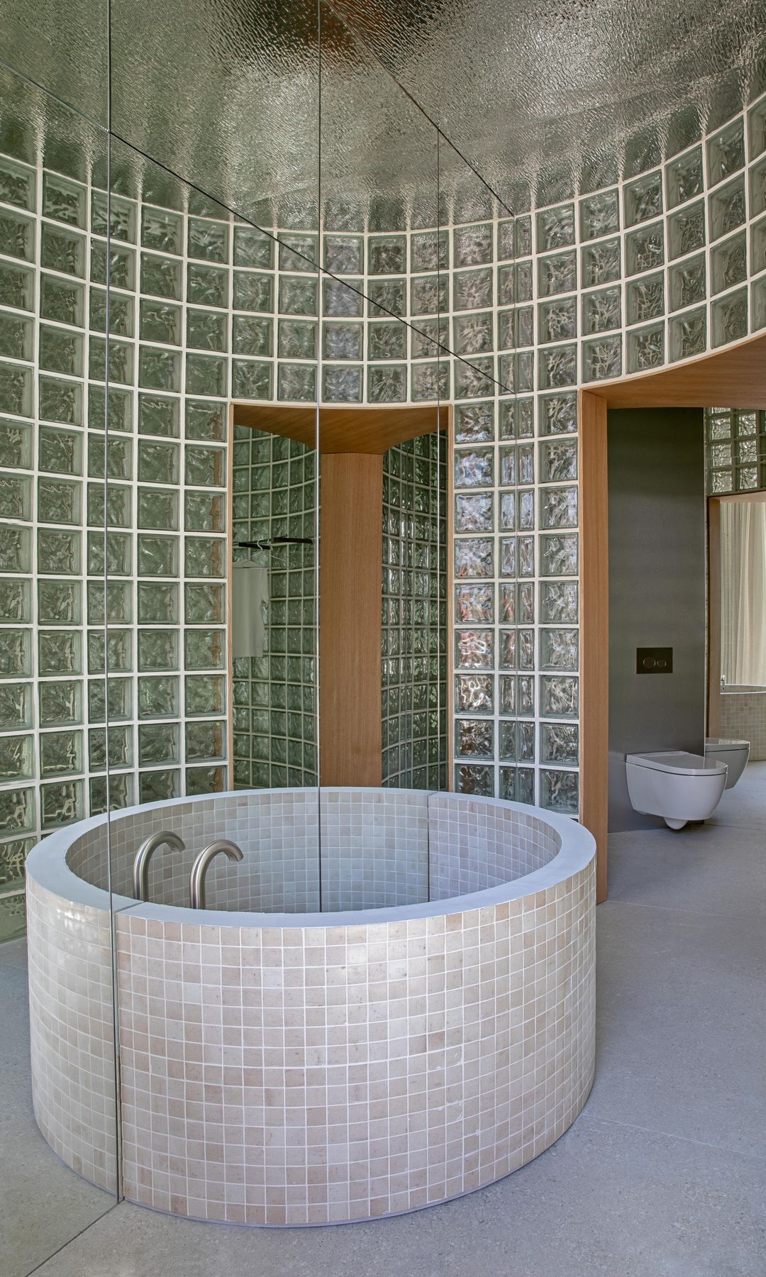 Baño con paredes curvas de pavés y bañera redonda 