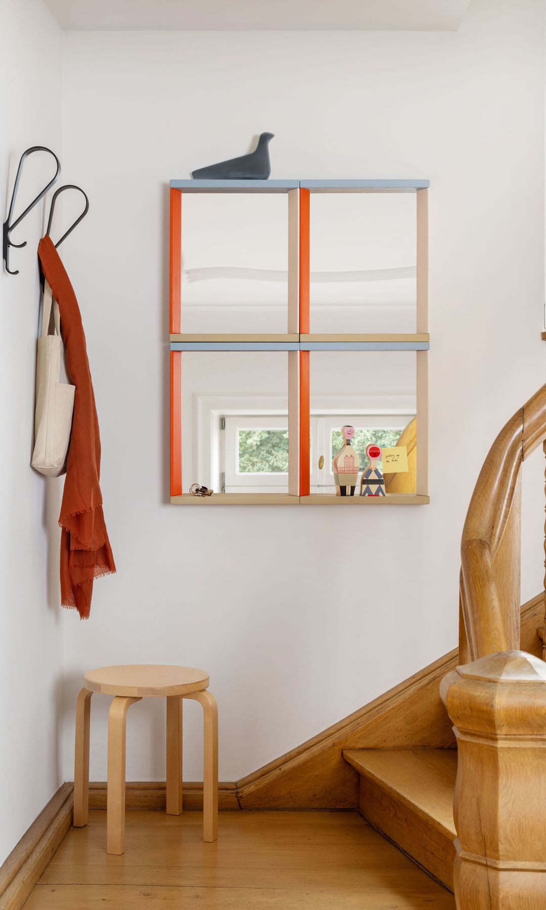 Recibidor con escalera con barandilla de madera, espejo de pared, taburete y perchero de pared 