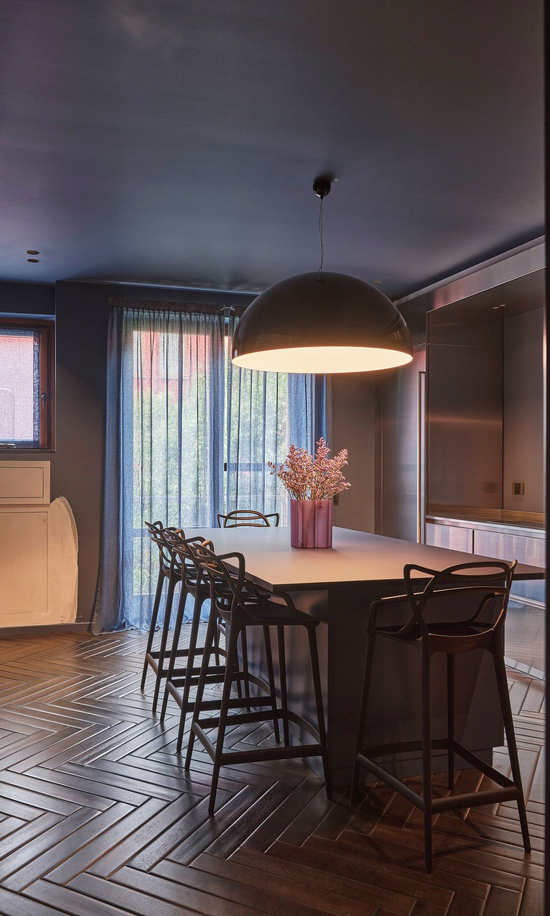 Comedor en la cocina con mesa alta con taburetes, lámpara de techo, jarrón, salida a terraza