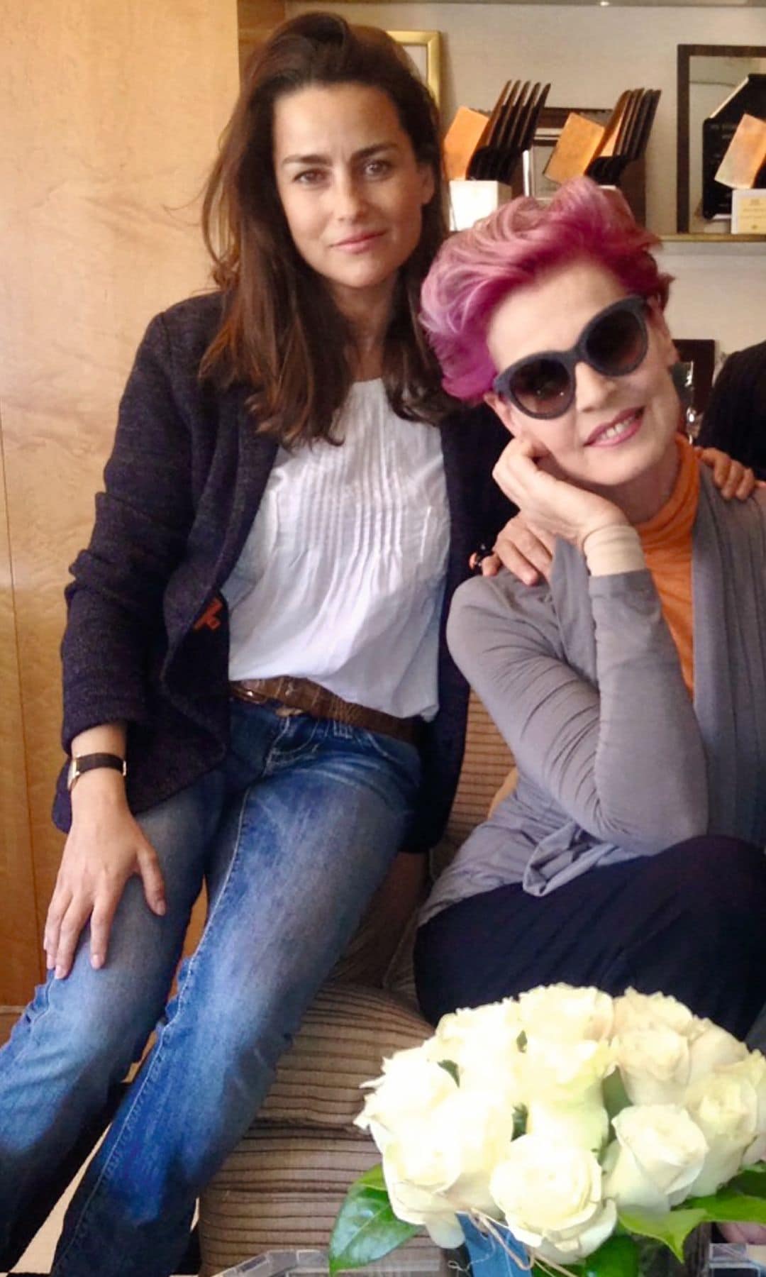 María Palacios con pantalones vaqueros y chaqueta sentada junto a Antonia dell’Atte con cabello rosa y gafas
