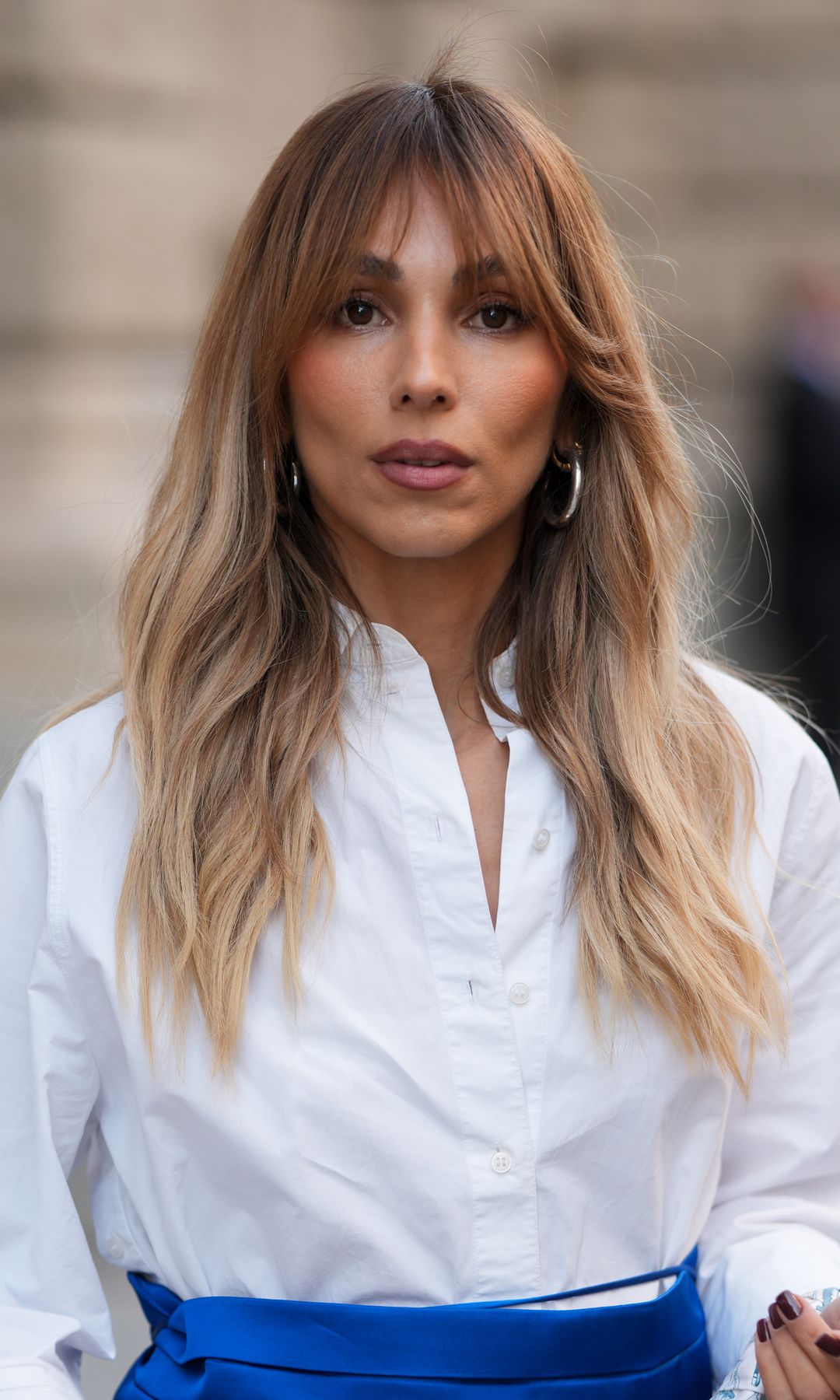 Mujer rubia con cabello a capas y flequillo abierto 