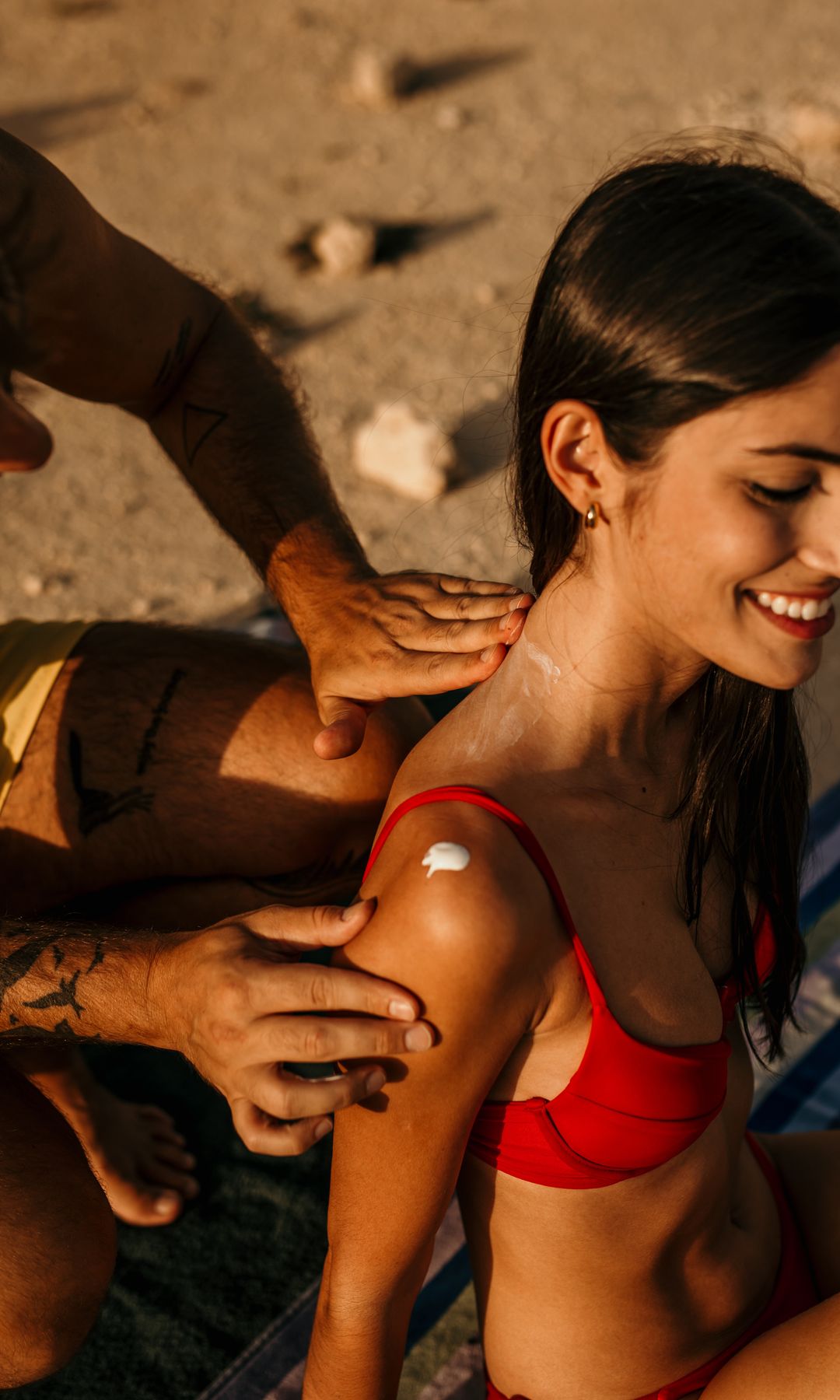 Un chico poniéndole protección solar a una chica en la playa