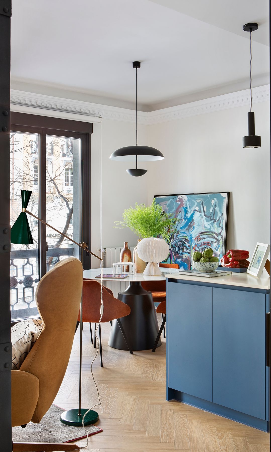 Cocina con comedor con mesa redonda, lámparas de techo negra, balcones, suelo de madera 