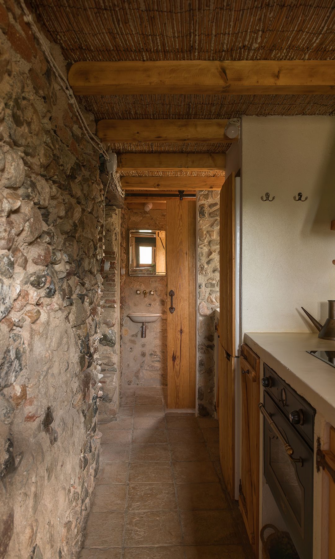 Aseo de cortesía comunicado con la cocina, paredes de piedra, lavabo suspendido, puerta corredera