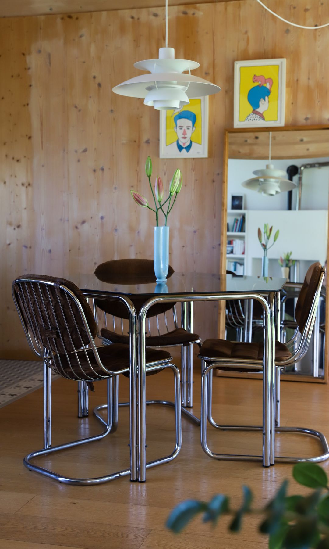 Comedor vintage con mesa redonda de cristal ahumado, sillas metálicas y negras, lámpara de techo