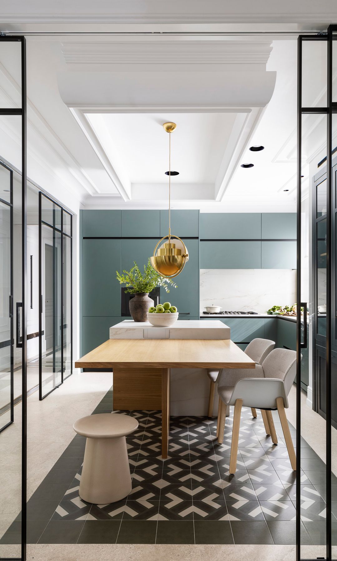 Cocina con isla y cerramiento de cristal con suelo geométrico y muebles de cocina oscura, isla con mesa de comedor anexa 