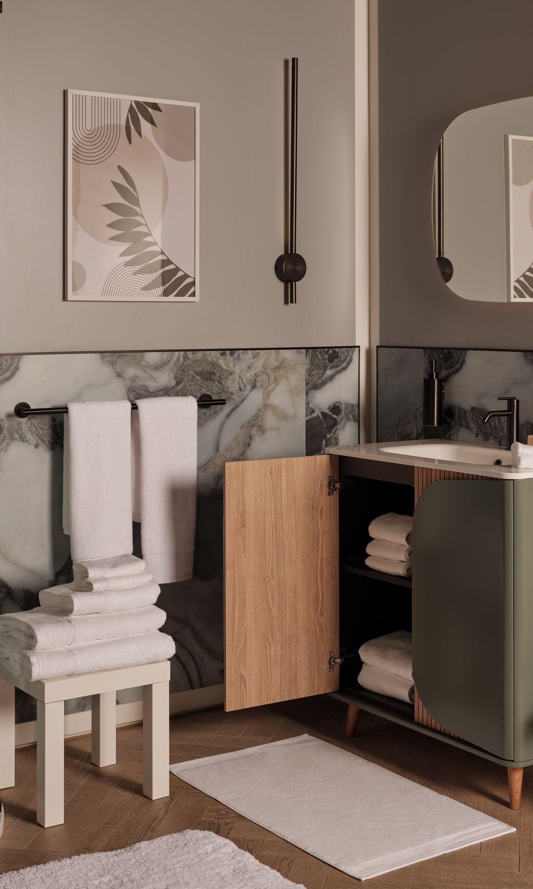 Baño pequeño con zócalo alto, mueble de lavabo verde, espejo ovalado, toallas blancas y alfombrilla blanca