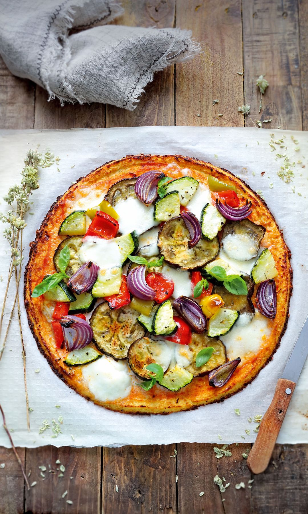 Pizza de coliflor, verduras asadas, mozzarella y albahaca
