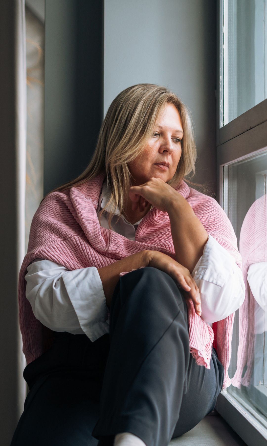 Mujer triste y pensativa mirando por la ventana