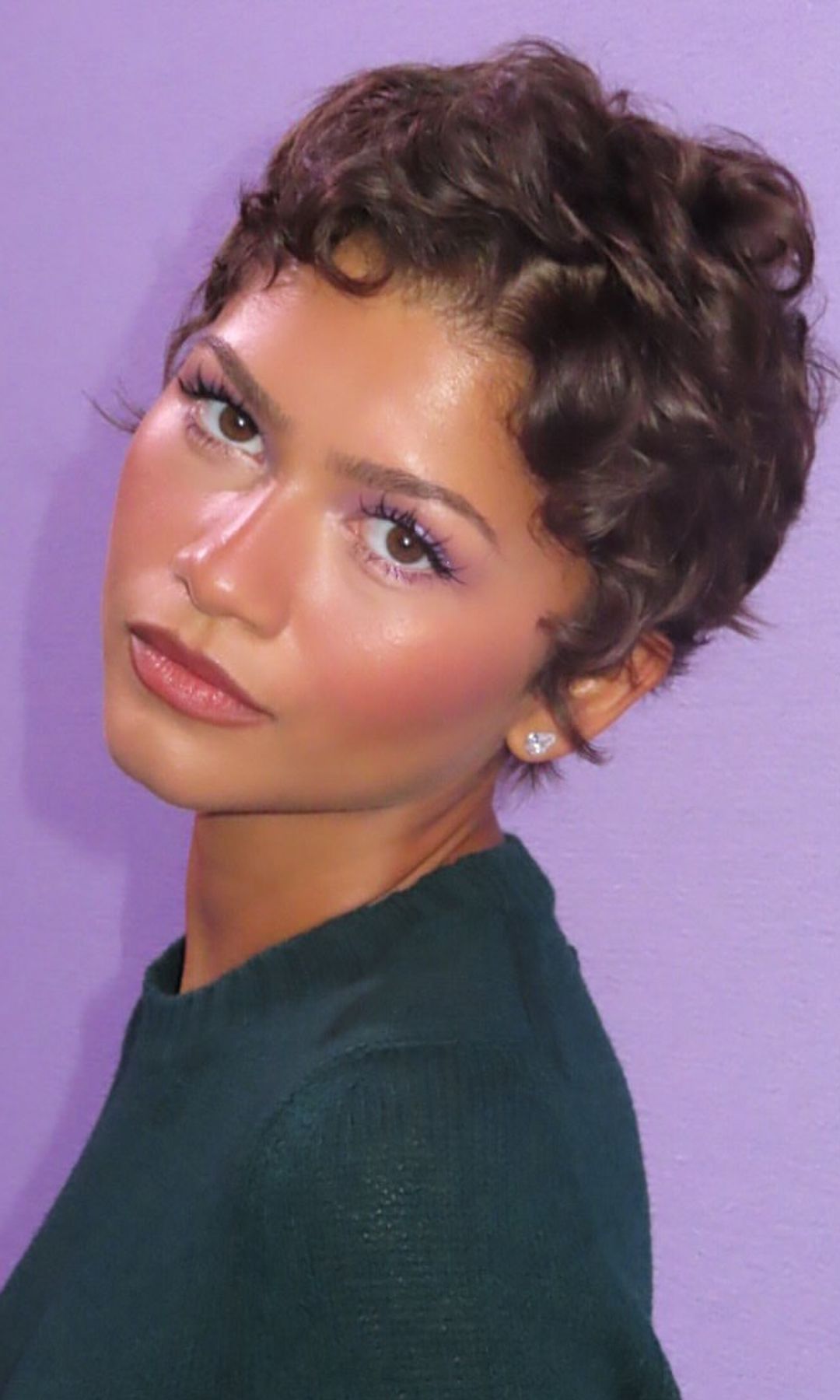 Zendaya con un corte pixie rizado y jersey verde en un evento de Prada Beauty.