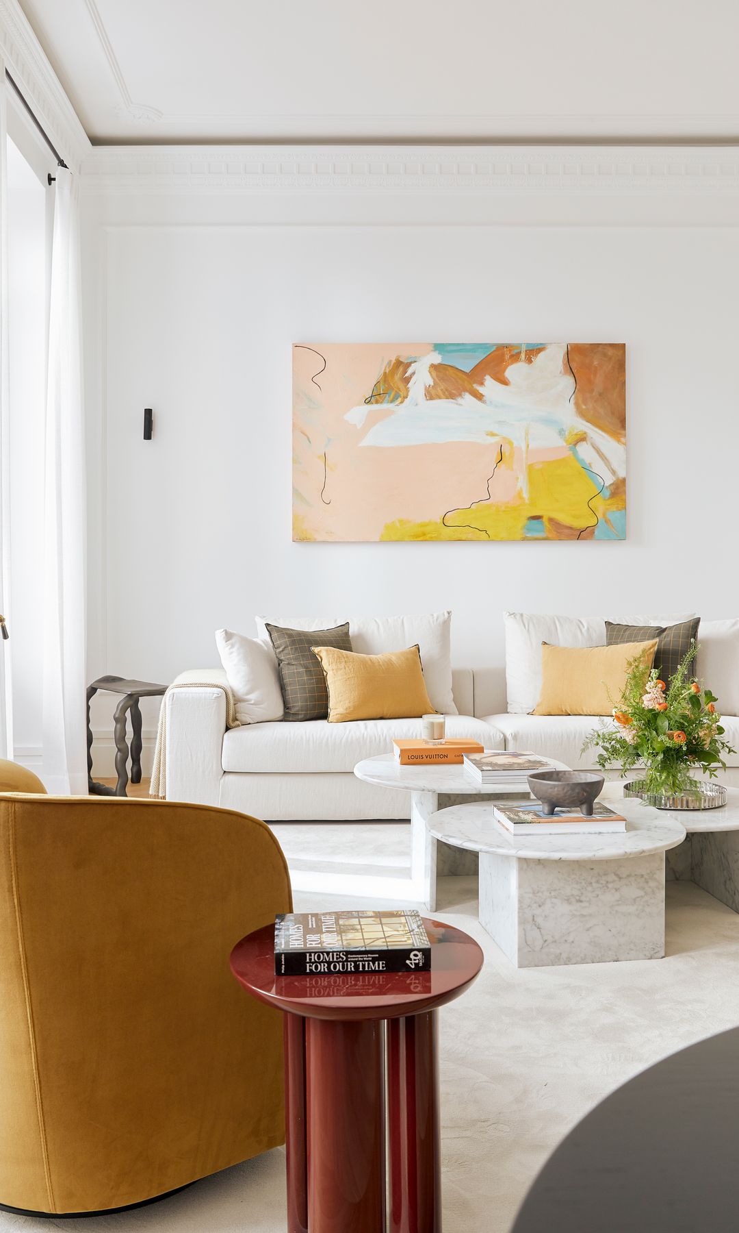 Salón con cuadro en la pared, sofá blanco, cojines blancos, amarillos y verdes, butaca y alfombra