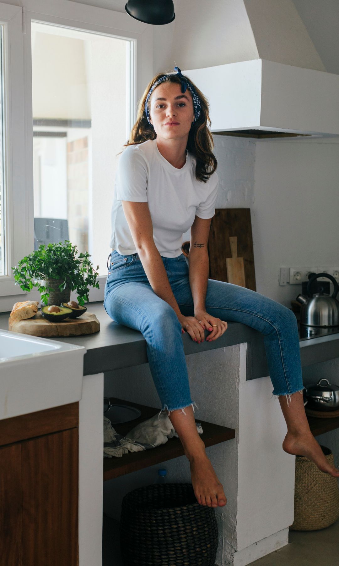 Mujer sentada sobre la encimera de la cocina 