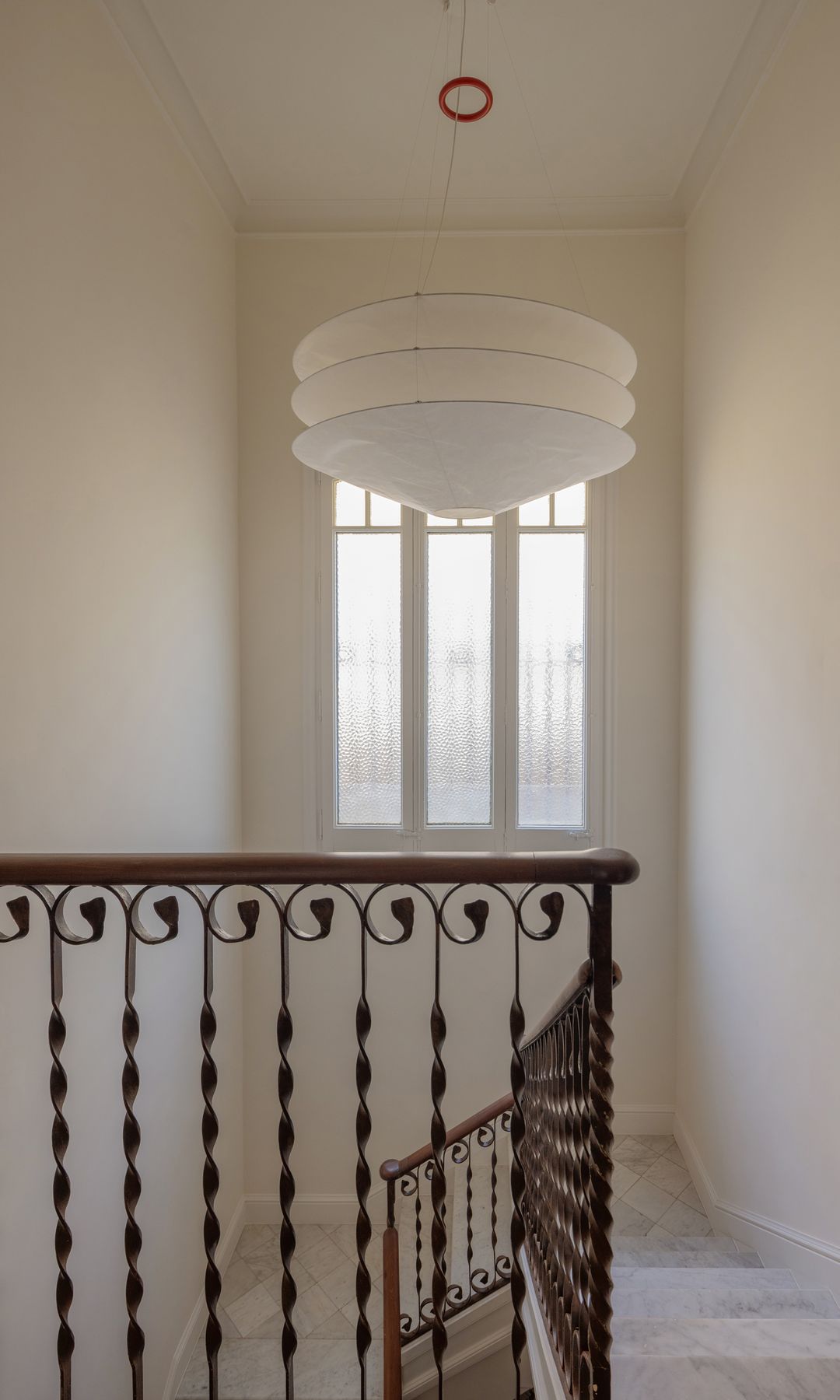 Escalera con barandilla de hierro, ventana lámpara de techo 