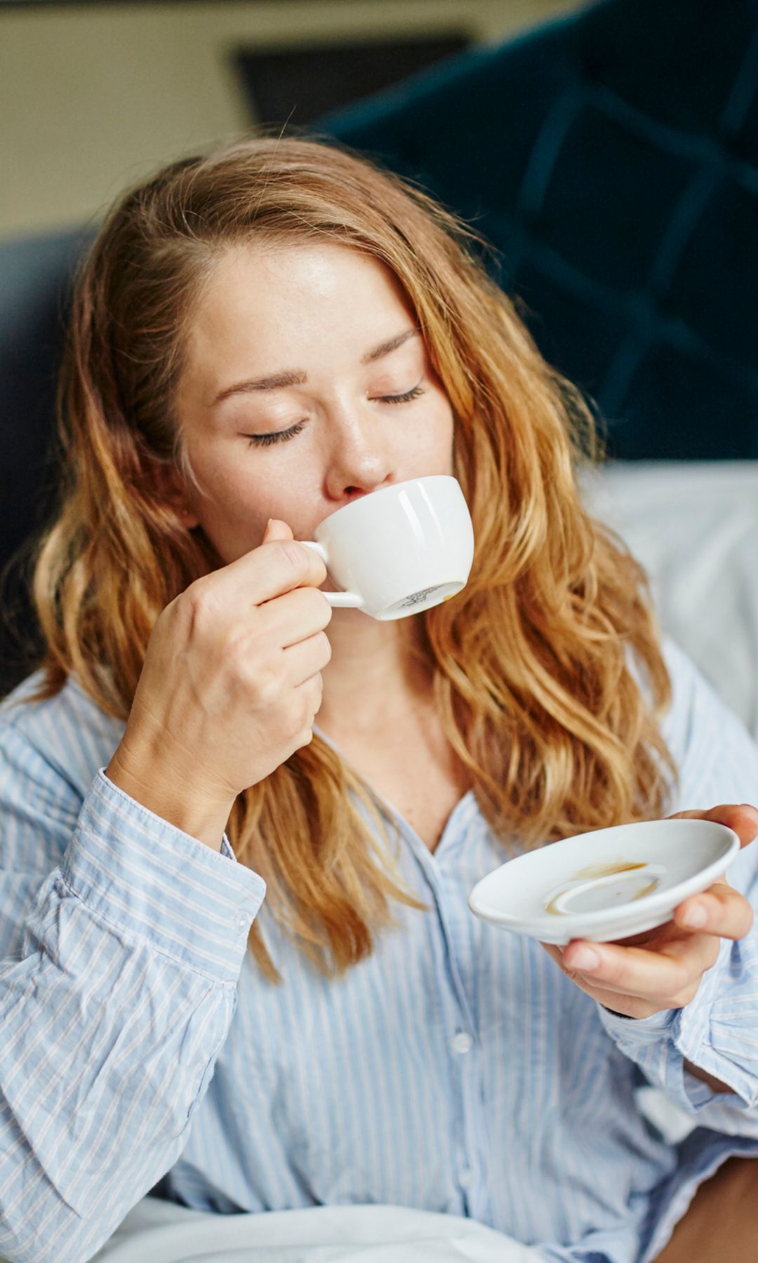 Una mujer tomándose un café en la cama