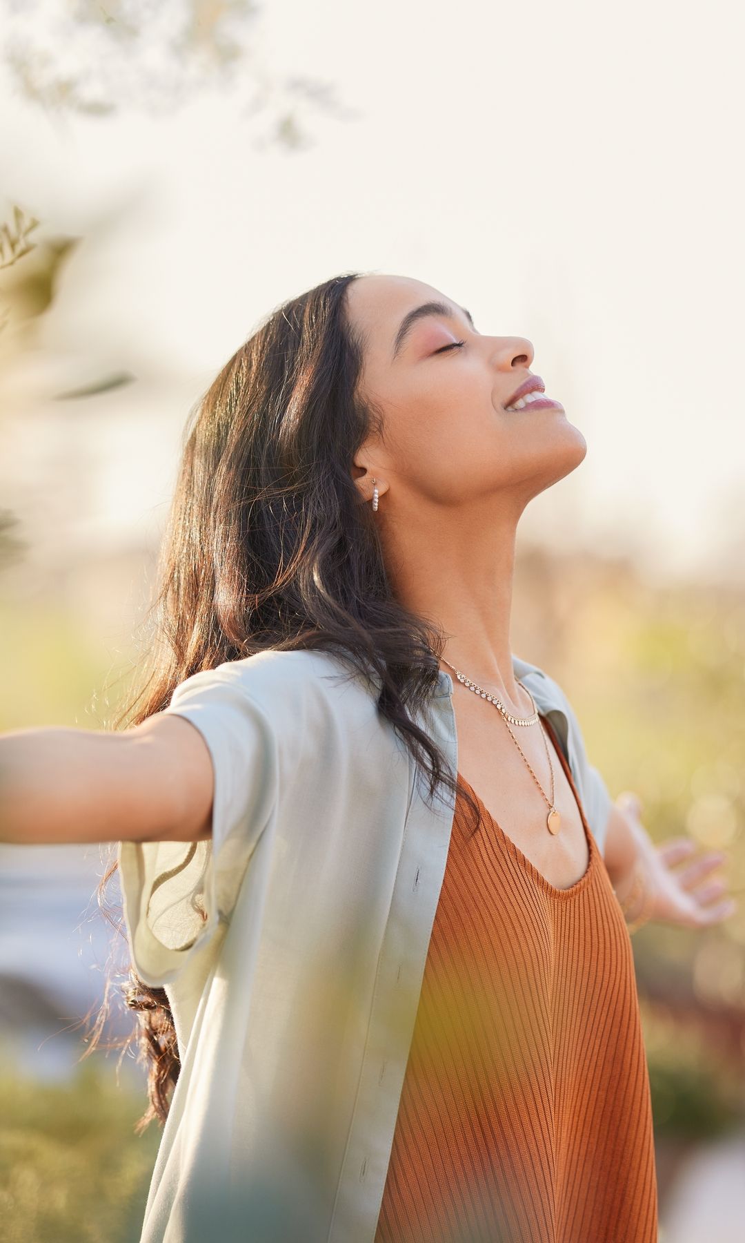 Mujer respirando al aire libre con los brazos abiertos