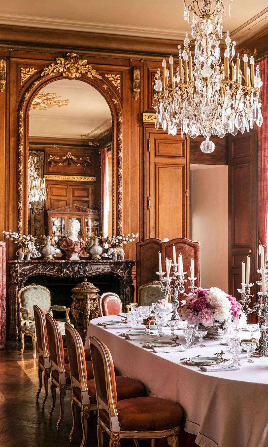 El majestuoso comedor, con capacidad para catorce comensales, conserva tapices originales del siglo XVIII, que envuelven el espacio en un aire de historia y distinción. La mesa luce arreglos de peonías, vajilla de porcelana antigua, cristalería tallada y cubertería con el escudo familiar grabado, un símbolo de la herencia nobiliaria