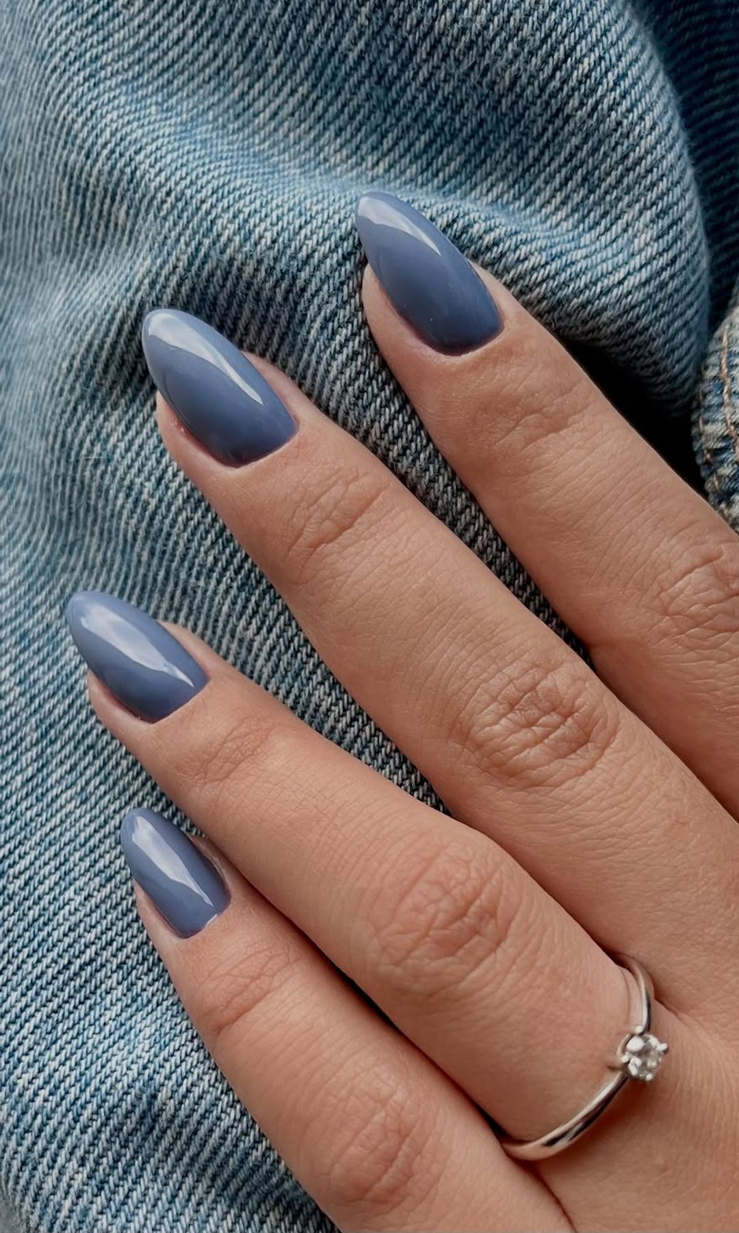 Manicura azul denim en uñas almendradas junto a tejido vaquero