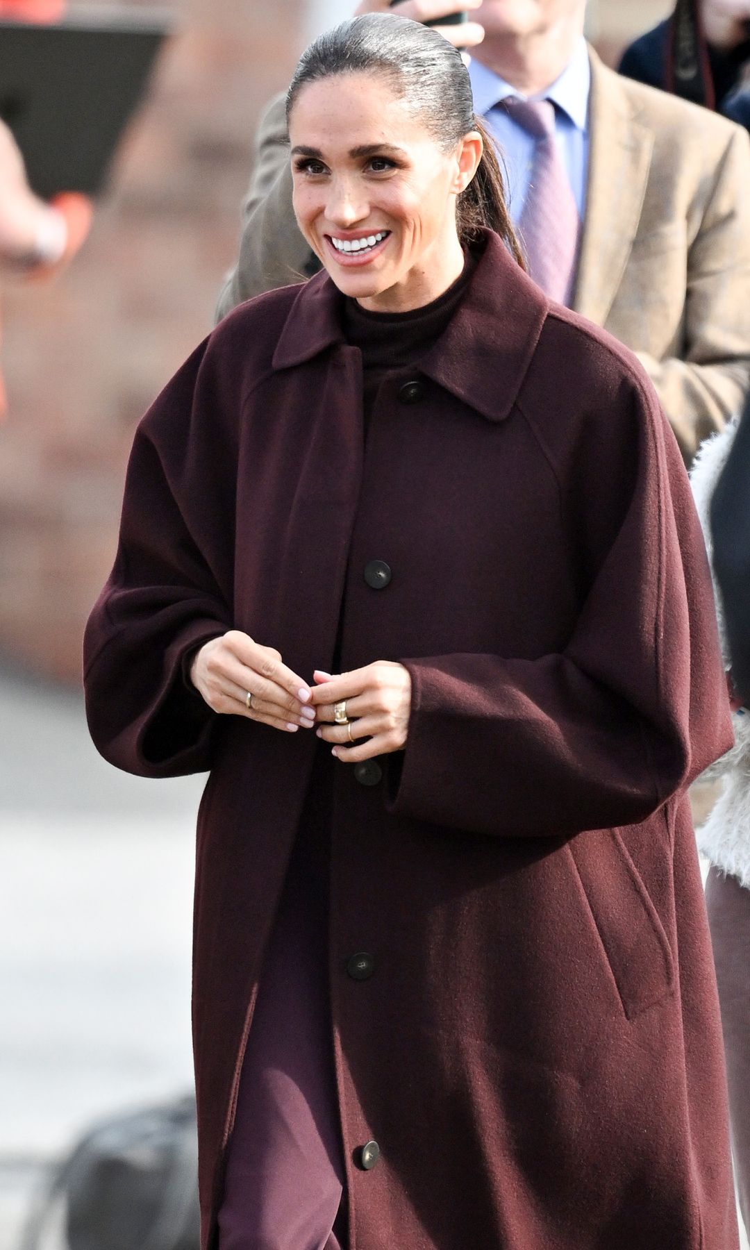 Meghan Markle, pura elegancia con un look que resume las tendencias de otoño: tonos berenjena, falda midi y abrigo de manga ancha