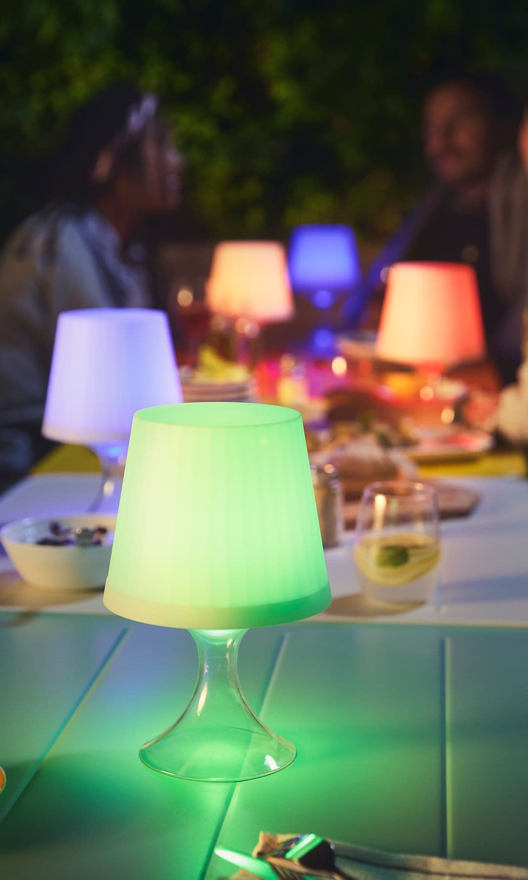 Lámpara IKEA sobre una mesa con gente en el jardín