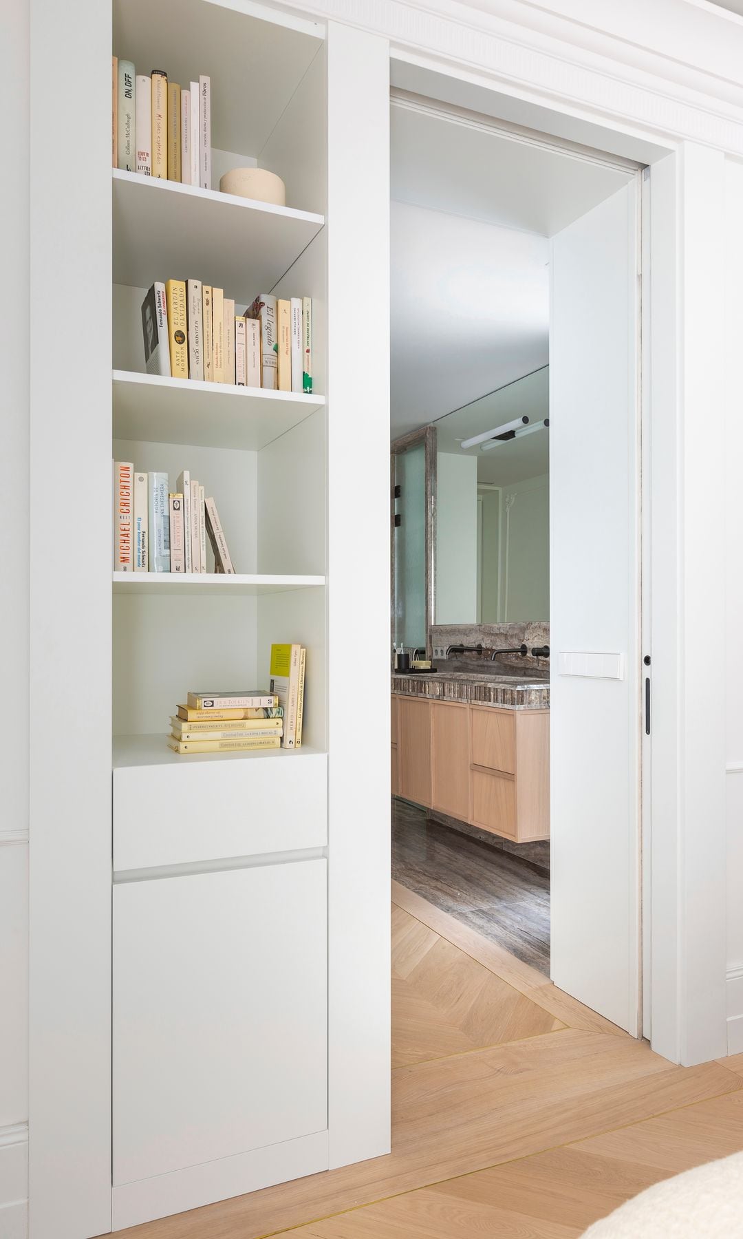 Dormitorio con pared blanca con estantería integrada en uno de los lados de la puerta