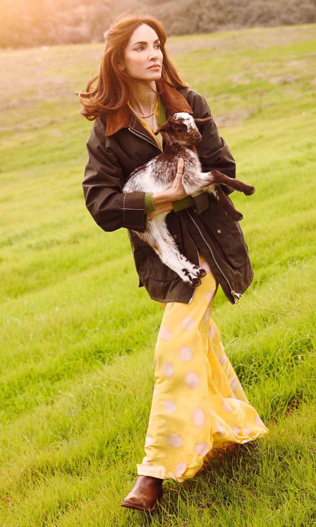 Eugenia Silva caminando en un campo con un cabrito en su casa de campo de Extremadura