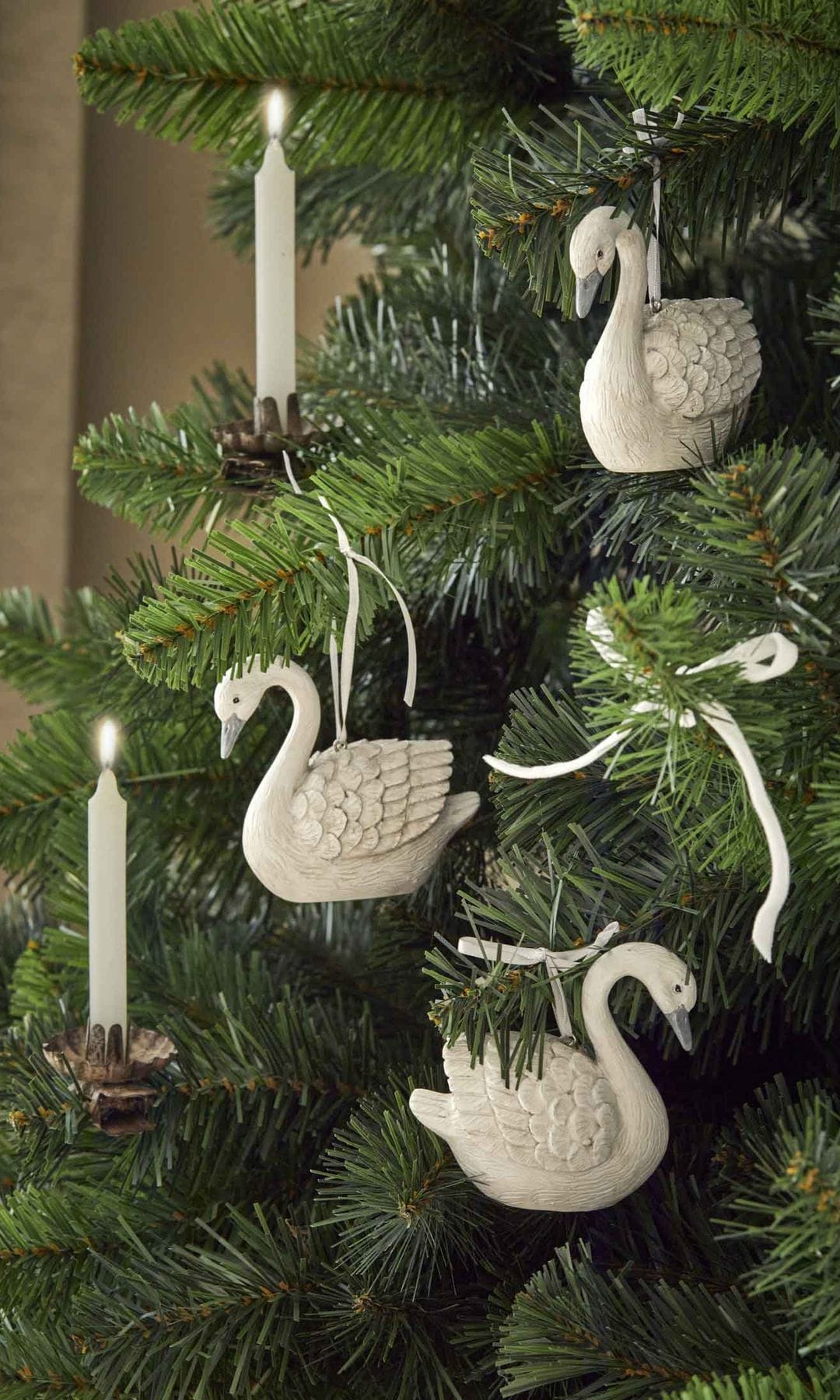 Árbol de Navidad con adornos blancos con forma de cisne y velas blancas