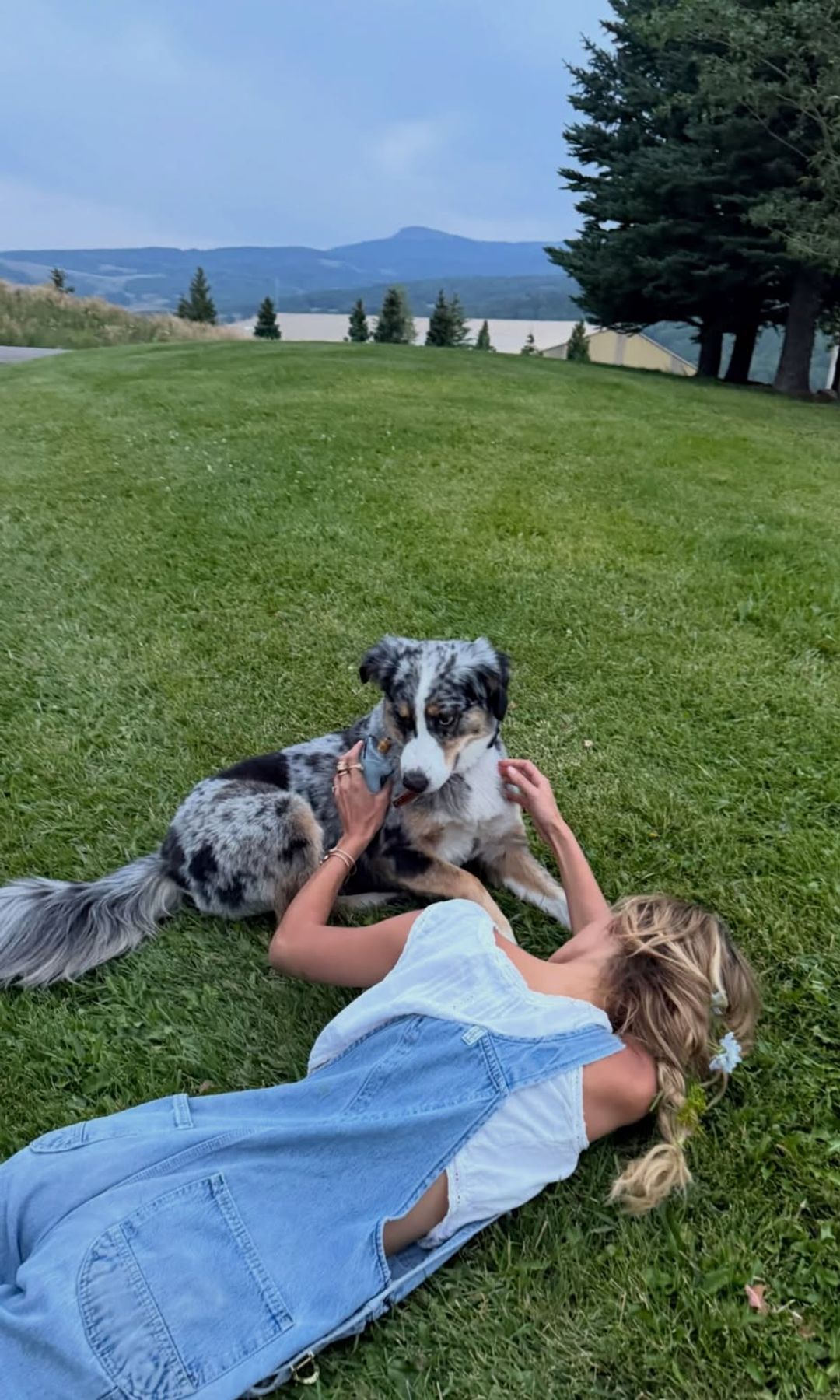 Bella Hadid tumbada en la hierba mientras acaricia a su perro